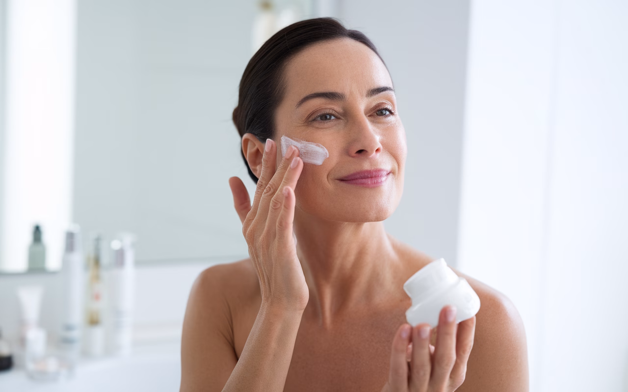 Skincare Routine for Mature Skin Woman applying anti-aging cream to her face in a bathroom